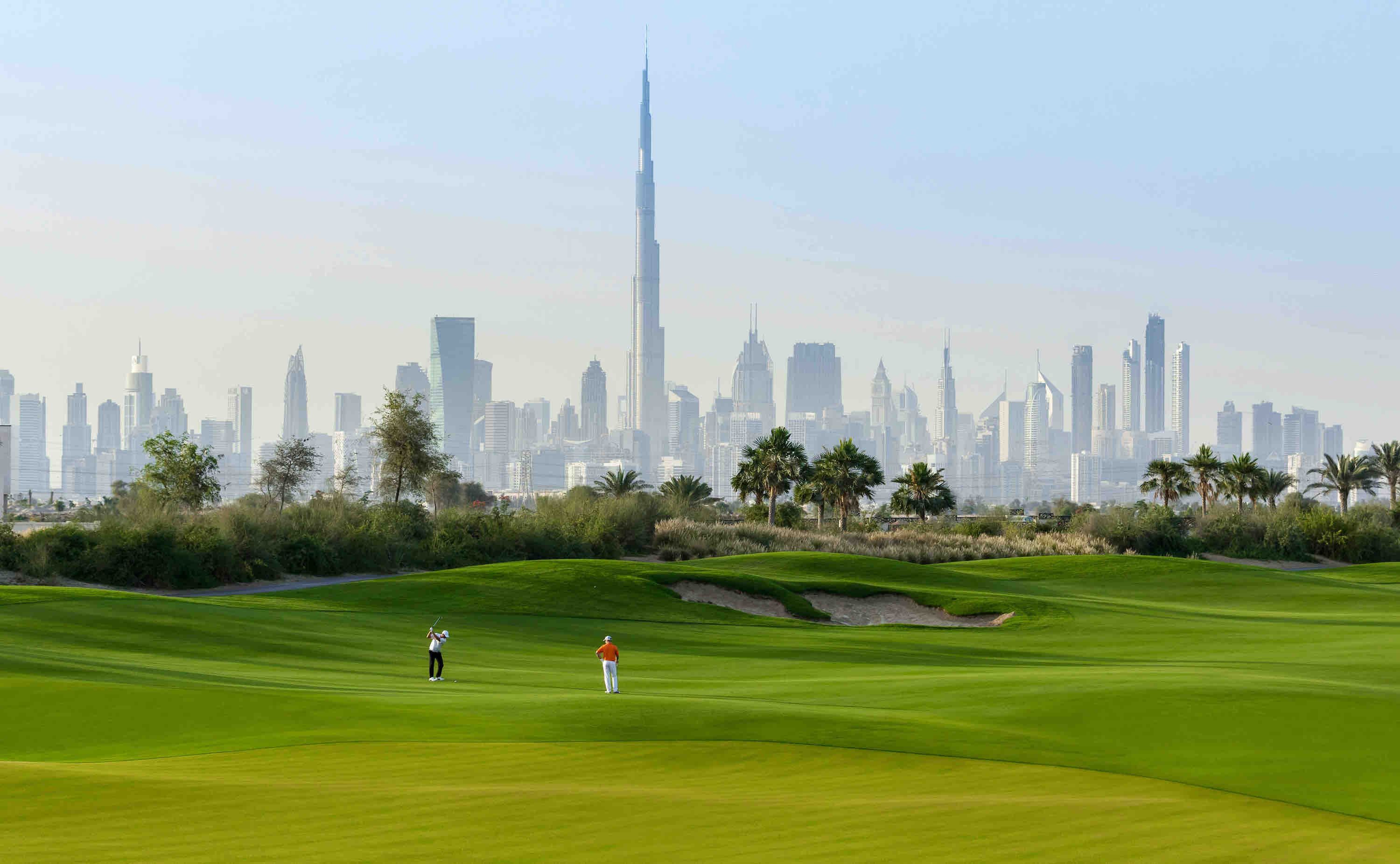 Golfers on the Dubai Hills course with the Burj Khalifa skyline behind