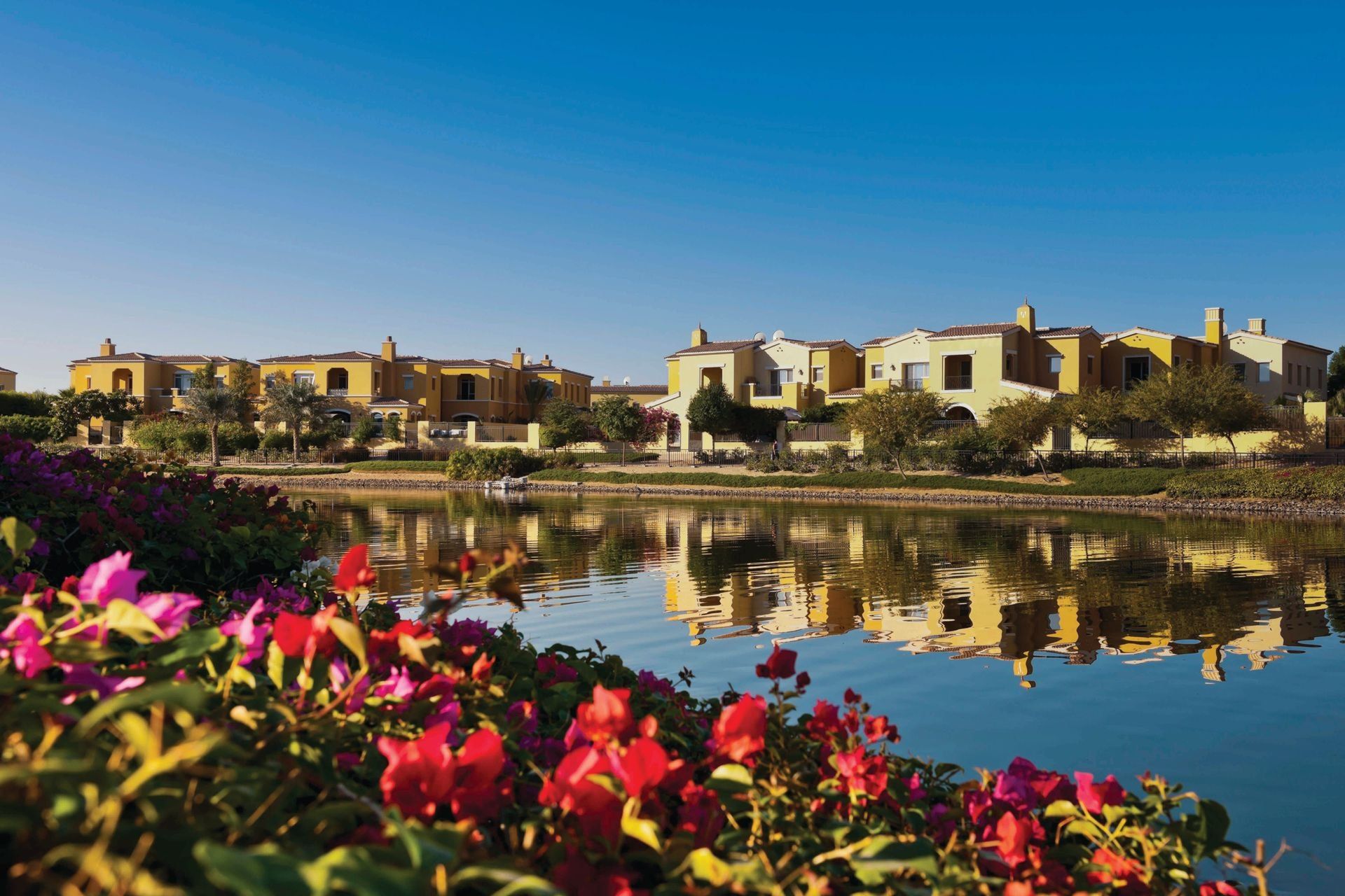 Villas across a lake, with bougainvillea in front