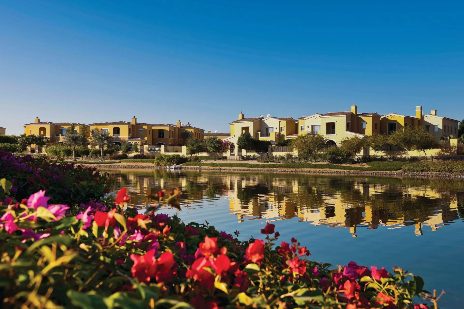 Villas across a lake, with bougainvillea in front